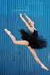 ballerina jumps by blue wall