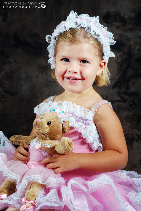 child poses with teddy bear