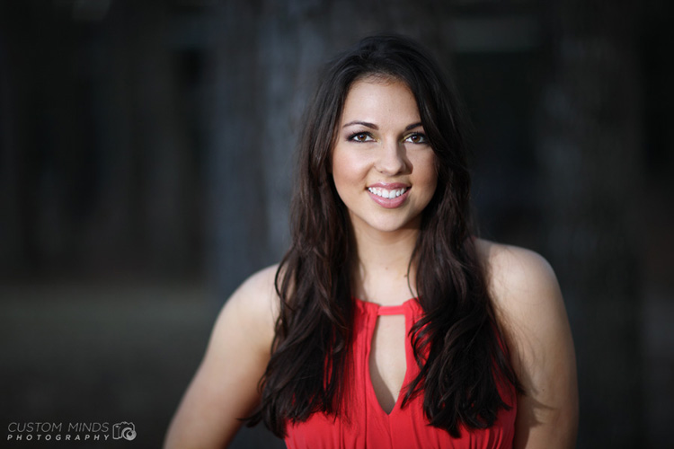 headshot with a red dress by a park at memorial