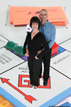 Happy couple smiles while standing on a Monopoly board - Greenscreen photo booth